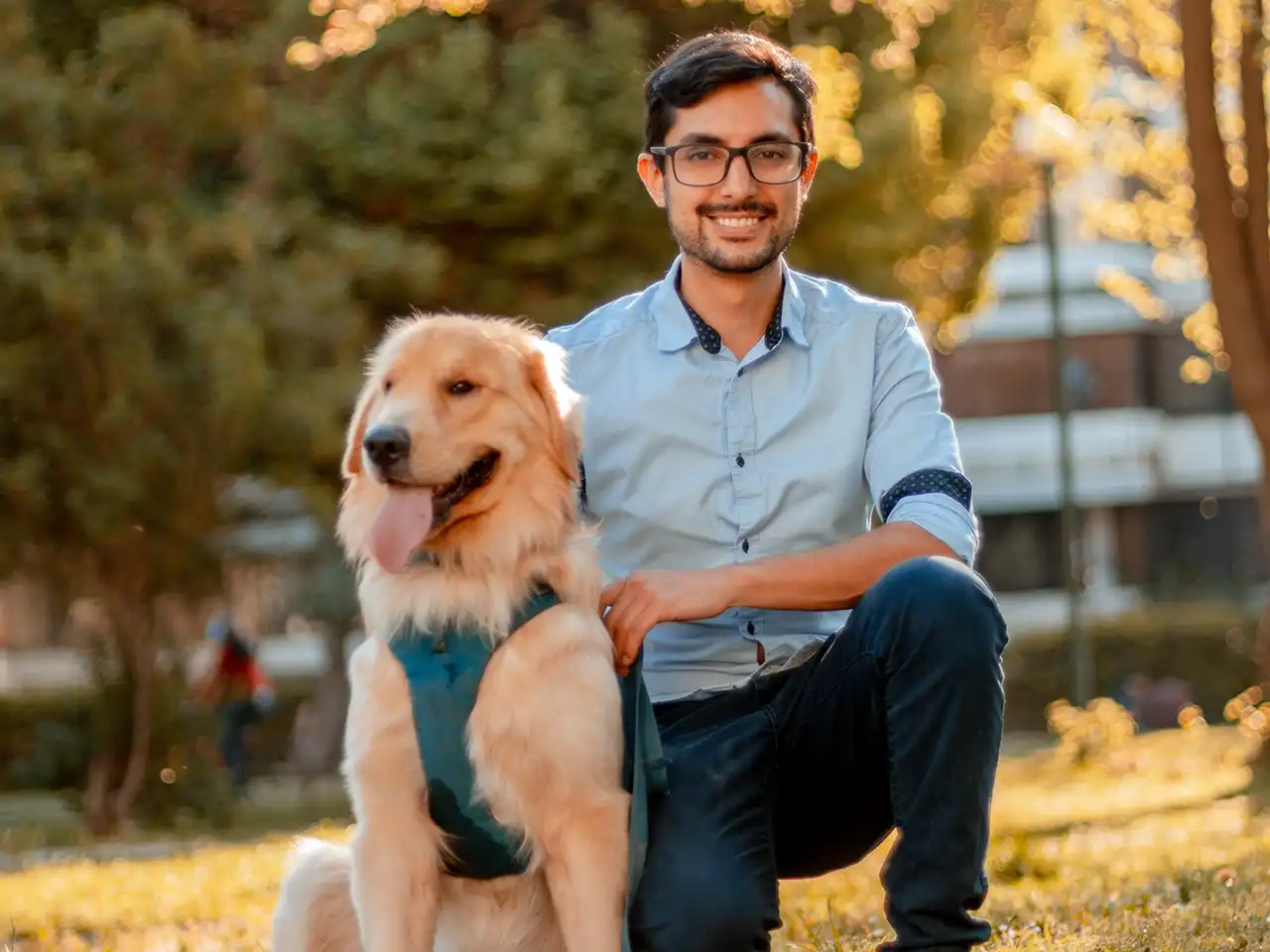 Man in blue dress shirt sitting beside brown dog during daytime